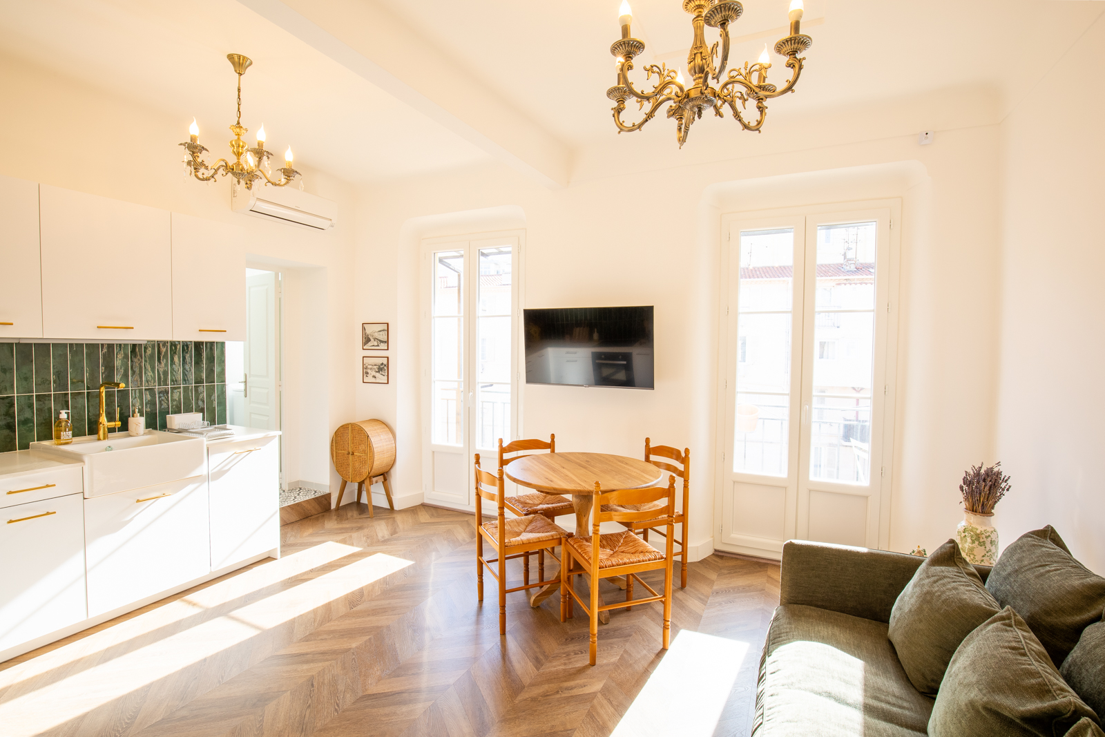 Light-filled apartment interior with a dining area, chandeliers and parquet floor