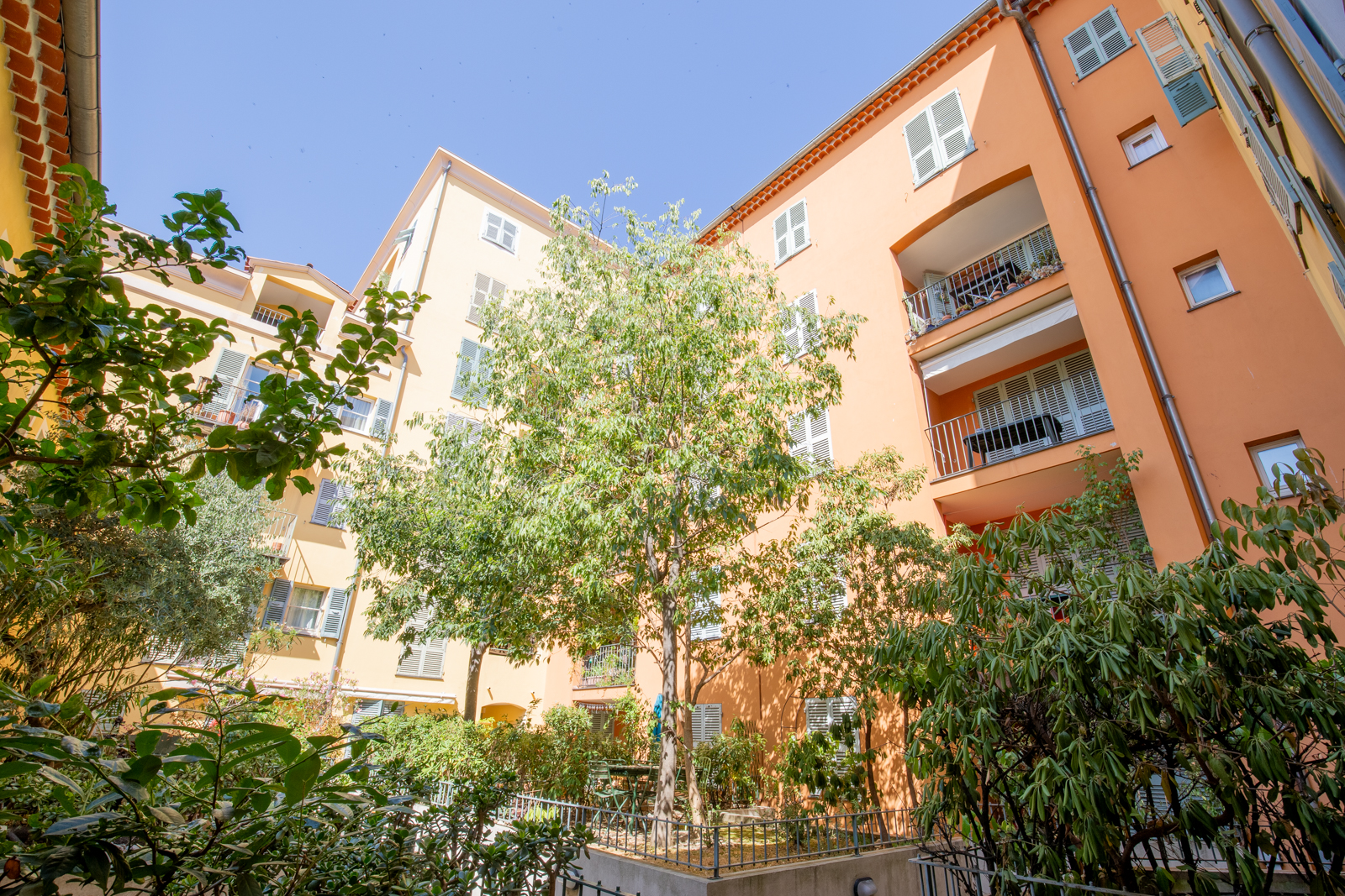 Apartment buildings with pale orange facades, balconies and a planted courtyard
