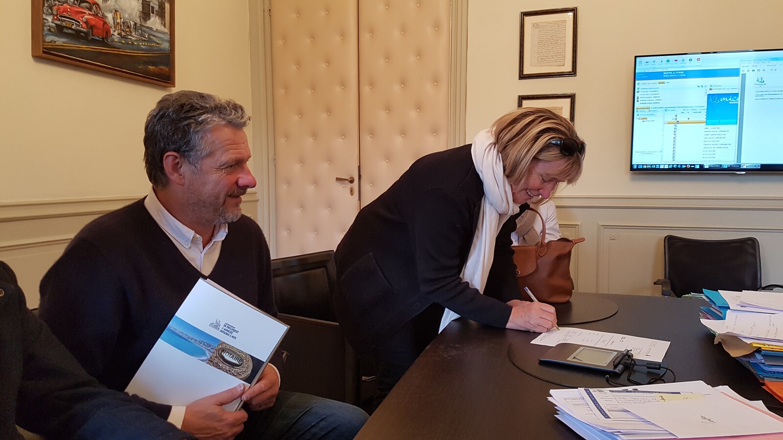 Clients signing property documents at a Notaire’s office